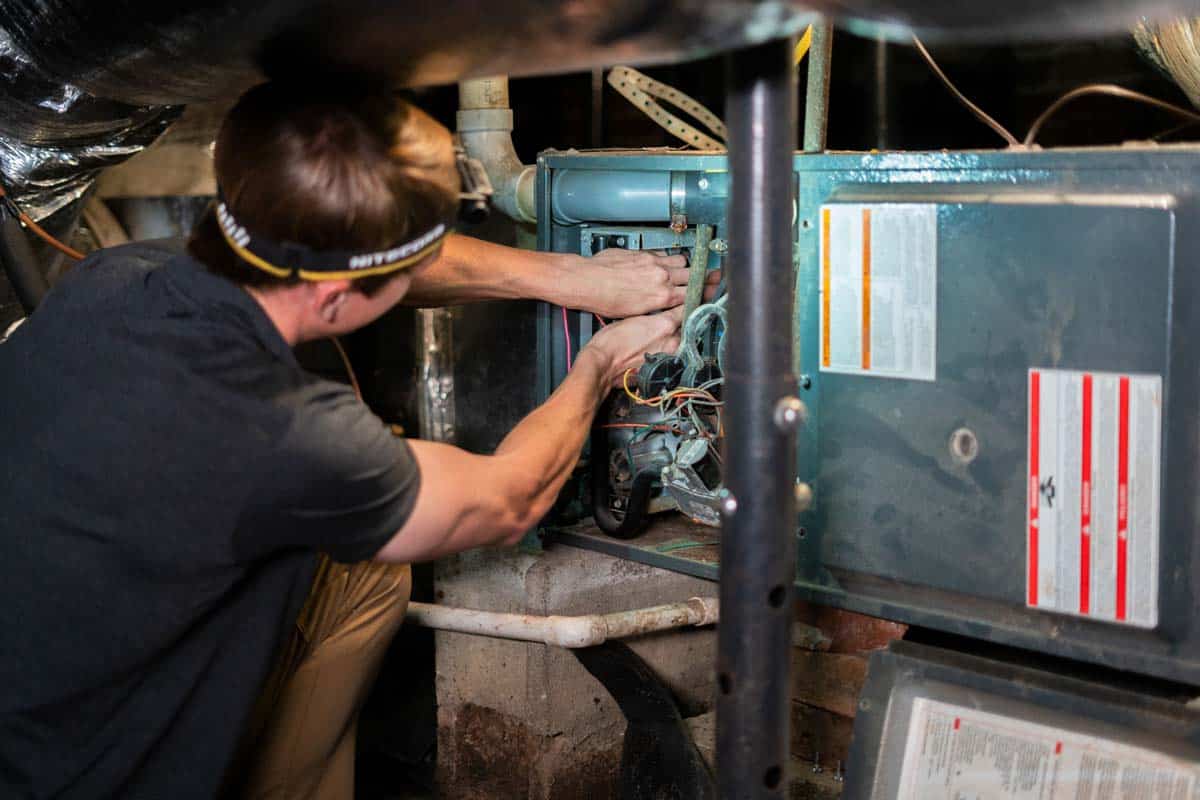 Heating, ventilation, and air conditioning professional making repairs in crawl space