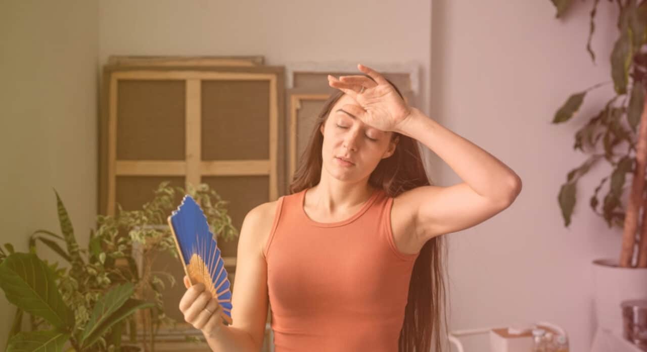 Woman using a fan to stay cool in the middle of summer, struggling to keep her home comfortable.